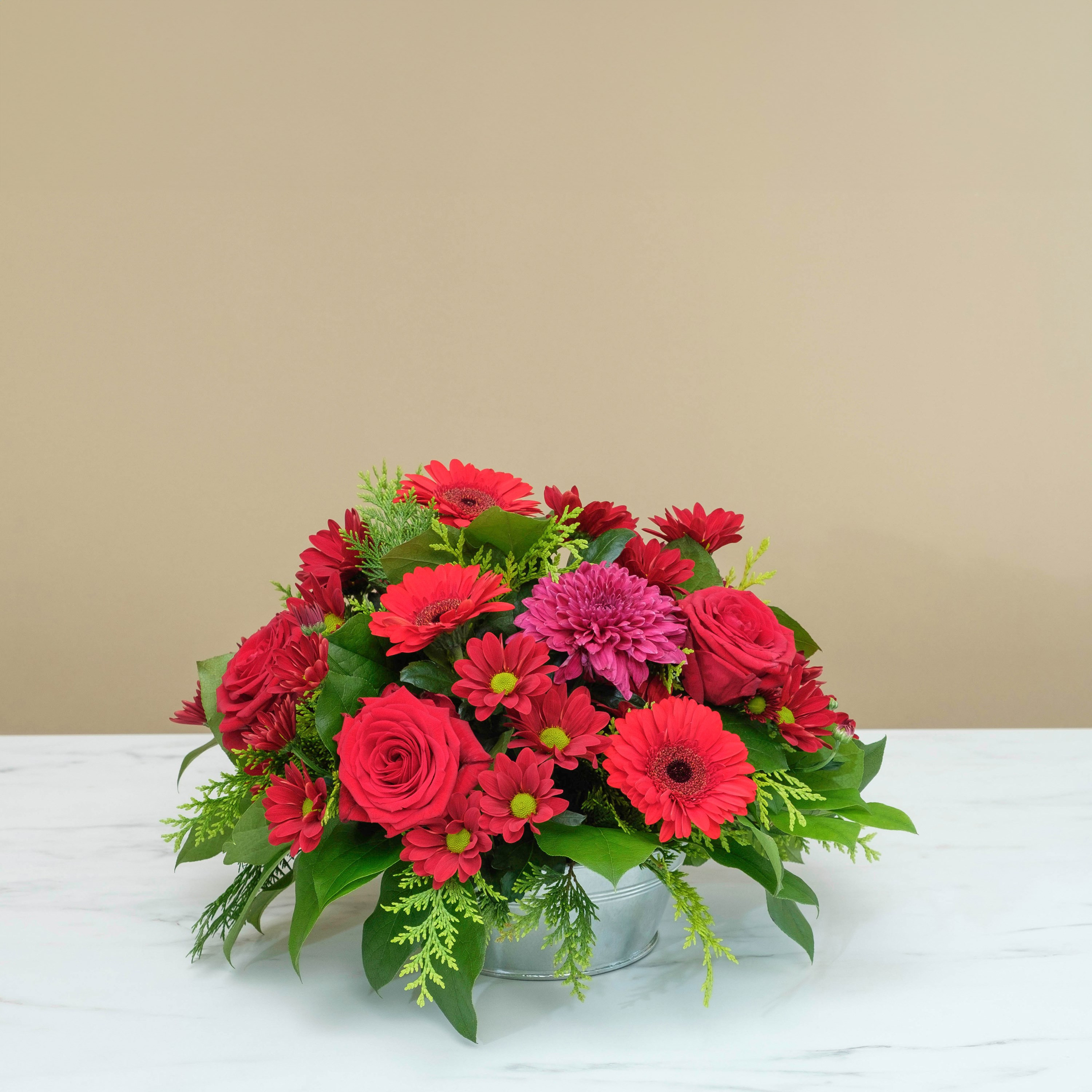 Wiązanka pogrzebowa w odcieniach czerwieni z róż, gerber i zieleni dekoracyjnej